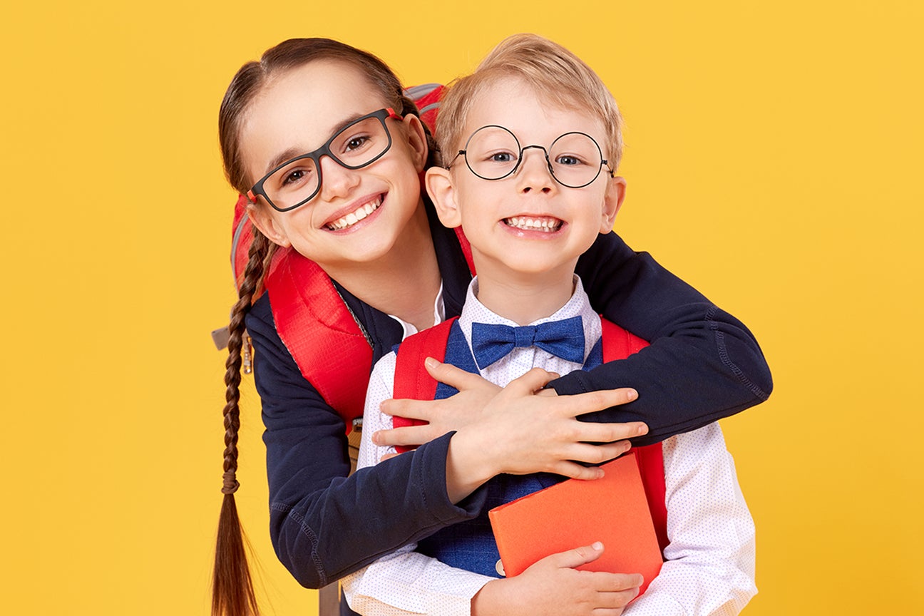 A photo of 2 young children dressed and ready for school.