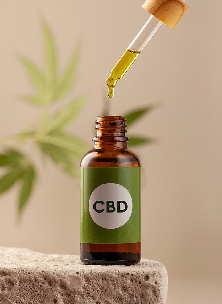 A bottle of cbd oil with a dropper being poured into it