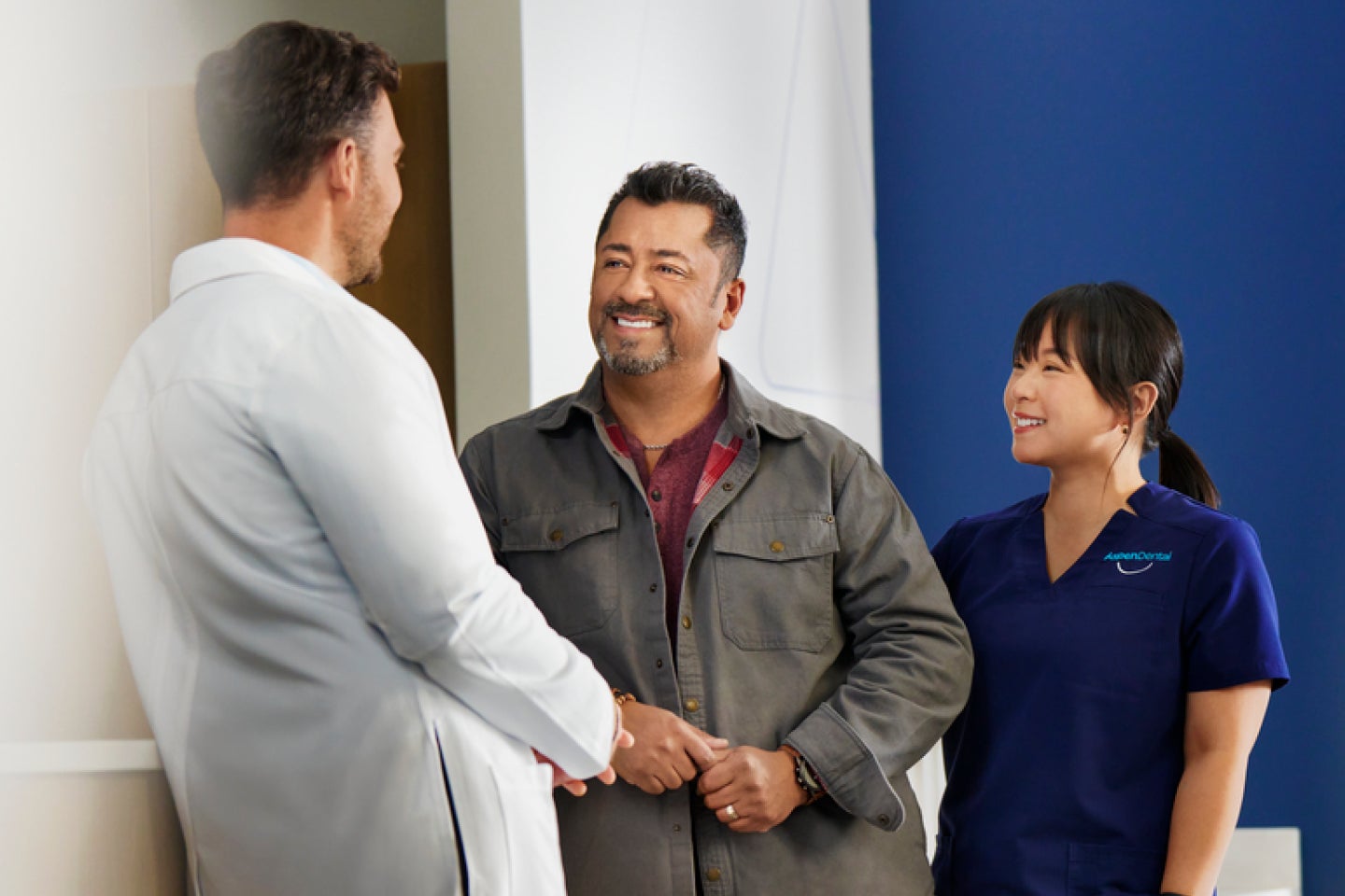 A man shaking hands with a doctor and a nurse