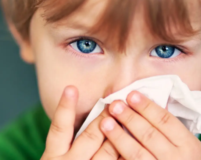 A child covering his mouth and nose with a piece of tissue paper