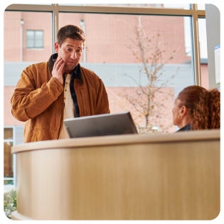 A man in a brown jacket is talking on a cell phone