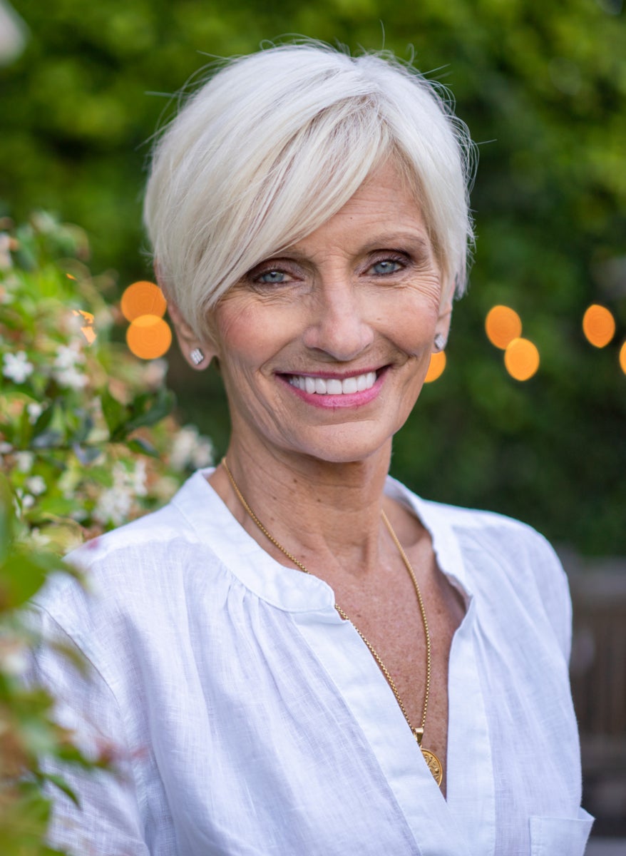 An image of a senior ClearChoice patient smiling in a flower garden.