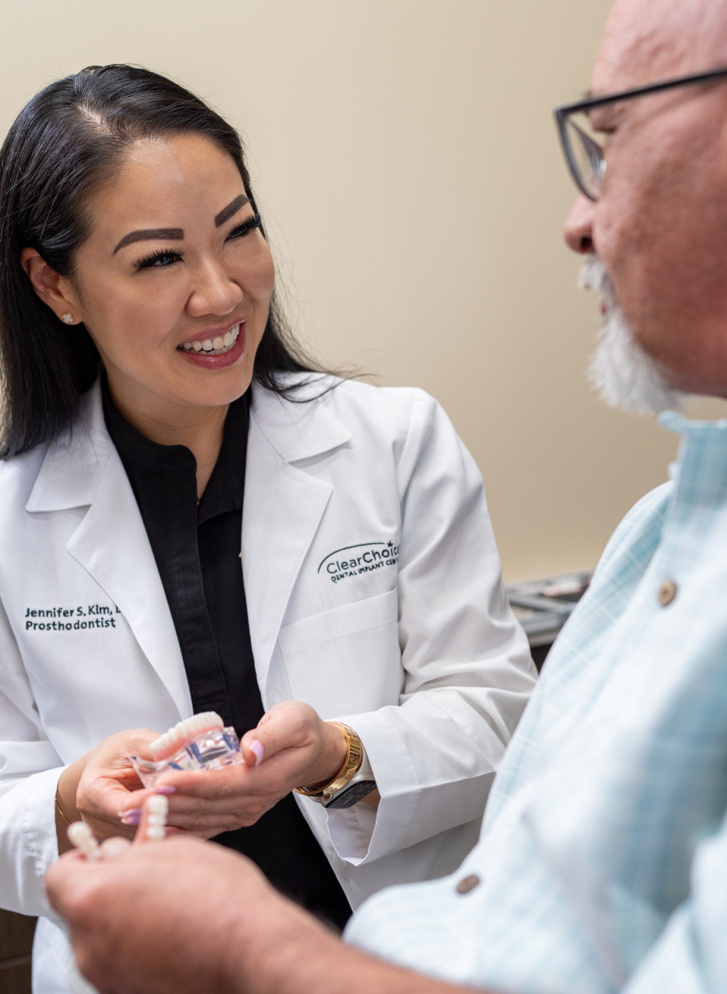 Dr. Jennifer Kim, ClearChoice Prosthodontist, discussing dental implants with Eric, a patient from ClearChoice Fort Worth, while showing him a dental model.