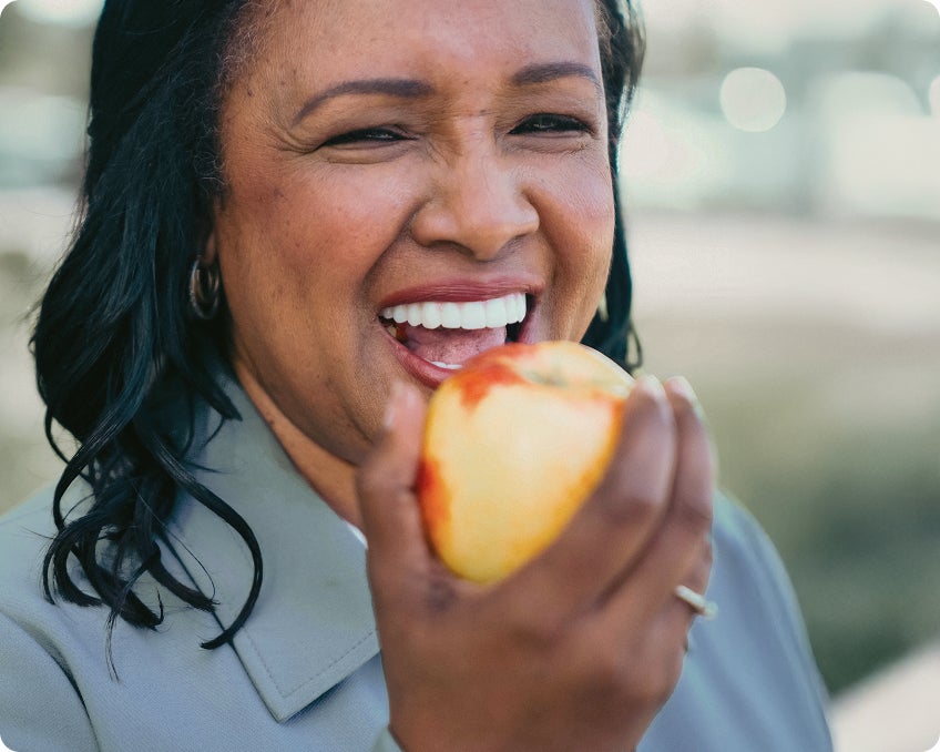 A ClearChoice patient enjoying an apple with her new dental implants, which were customized to feel and look uniquely her.