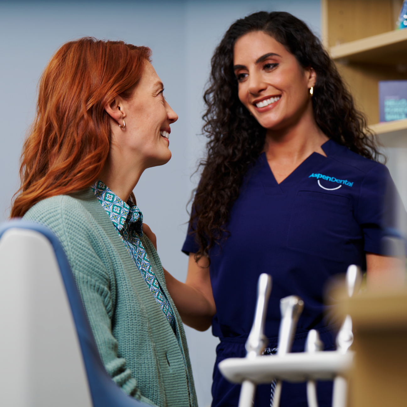 A friendly Aspen Dental professional smiling while consulting with a patient about front tooth implant options, emphasizing personalized care and expertise.