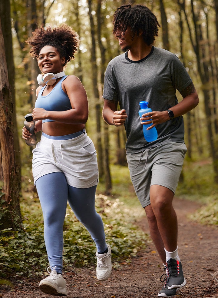 A man and a woman are jogging in the woods