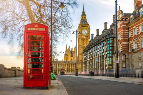 Red telephone cabin on a London street with Big Ben and Westminster Palace in the background in winter