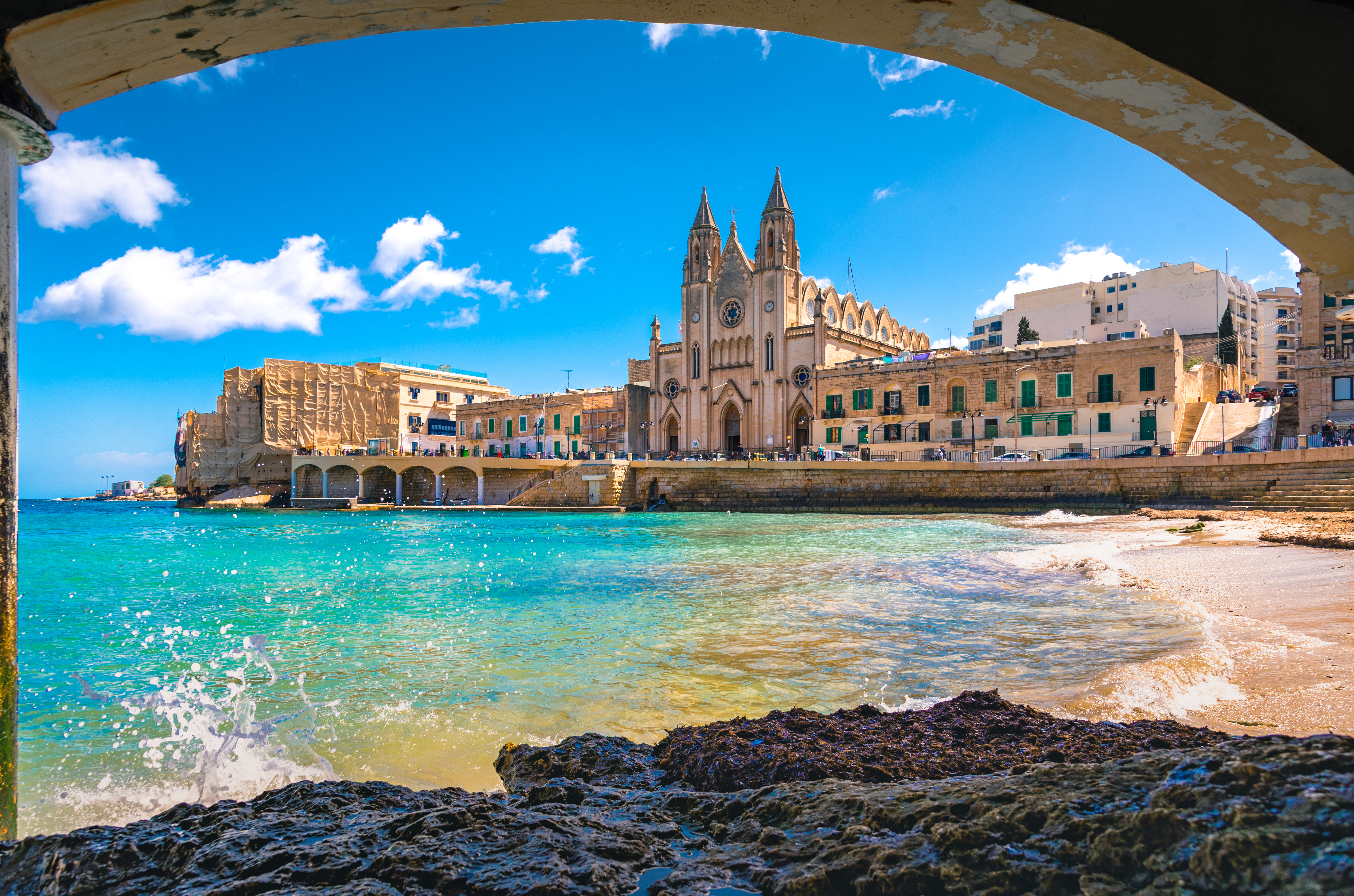 Saint Julian's beach in Malta with historic buildings in the background, including the iconic Balluta Buildings overlooking Balluta Bay