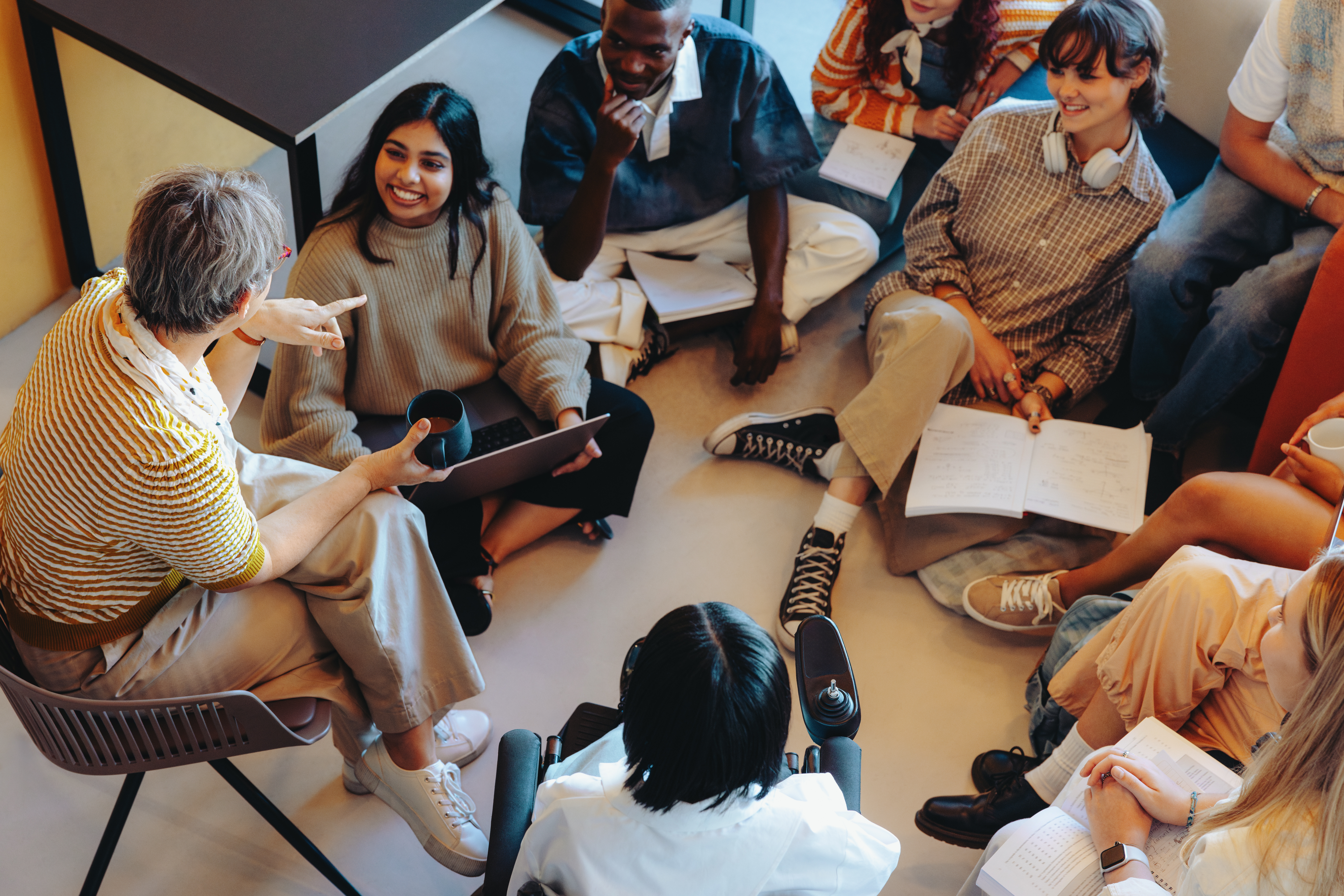 Teacher leading a casual discussion in a diverse classroom group setting with engaged students sitting in a circle on the floor