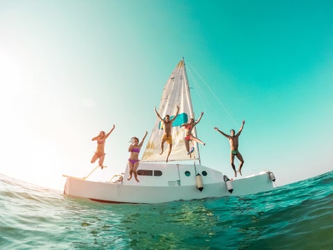 Friends jumping into tropical ocean water in Miami, Florida, enjoying a sunny beach day