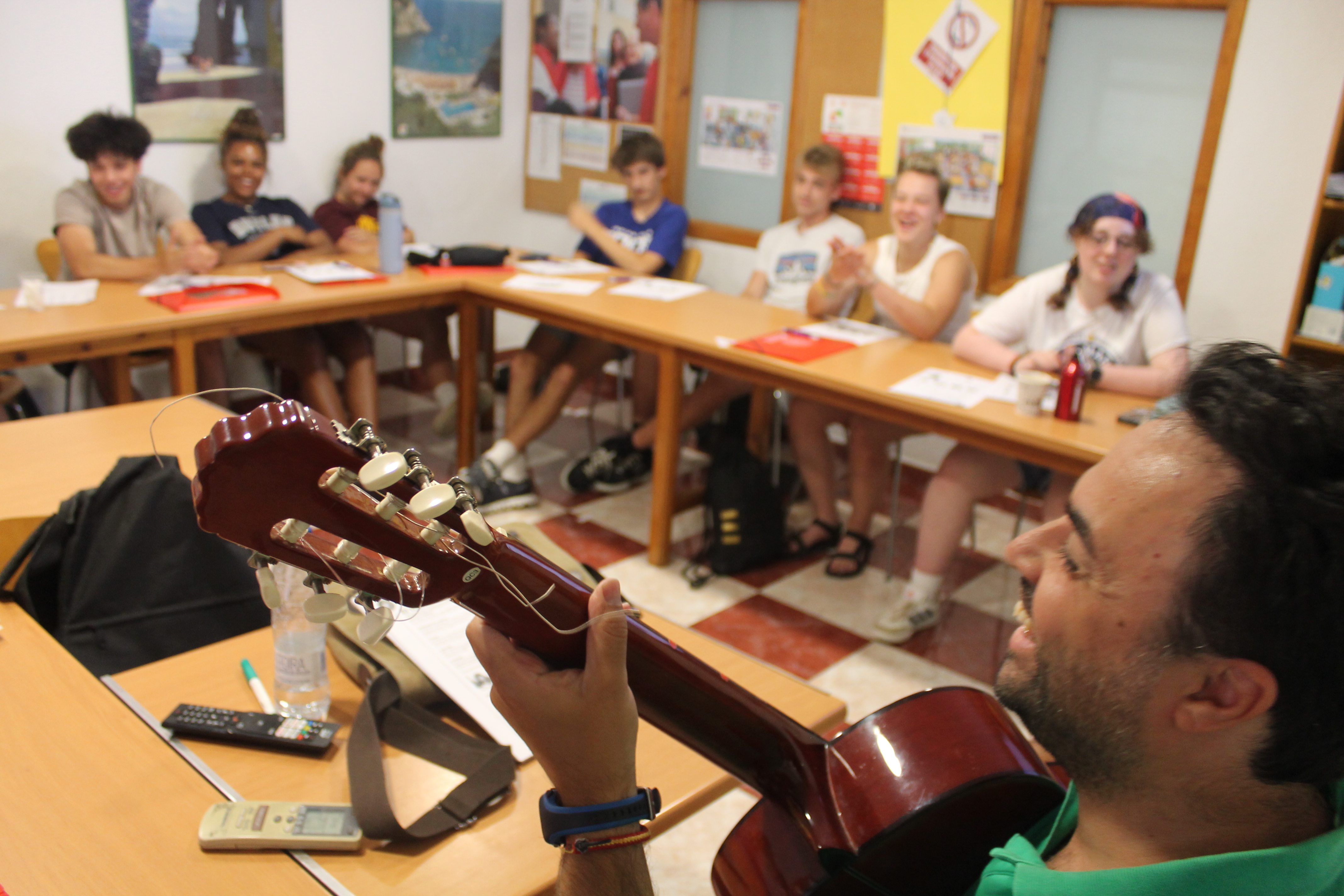 Students in classroom in Malaga with teacher playing guitar