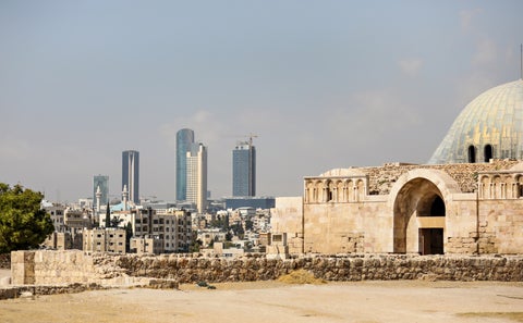 Roman ruins in the middle of the ancient citadel park in the center of Amman with modern skyscrapers in the background, Jordan