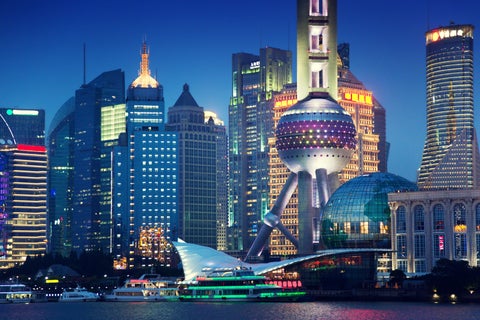 Aerial view of urban landscape with towering skyscrapers, modern shopping complexes, and Huangpu River at night in Shanghai, China