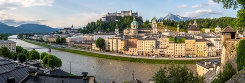 The historic Hohensalzburg Fortress stands proudly on a hill, overlooking the old town with its baroque domes and spires, all set against the backdrop of the Alps in Vienna, Austria