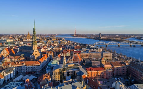 Aerial view of Riga, Latvia, showing the Daugava River, Vanšu Bridge, and the Riga Cathedral in the historic city center