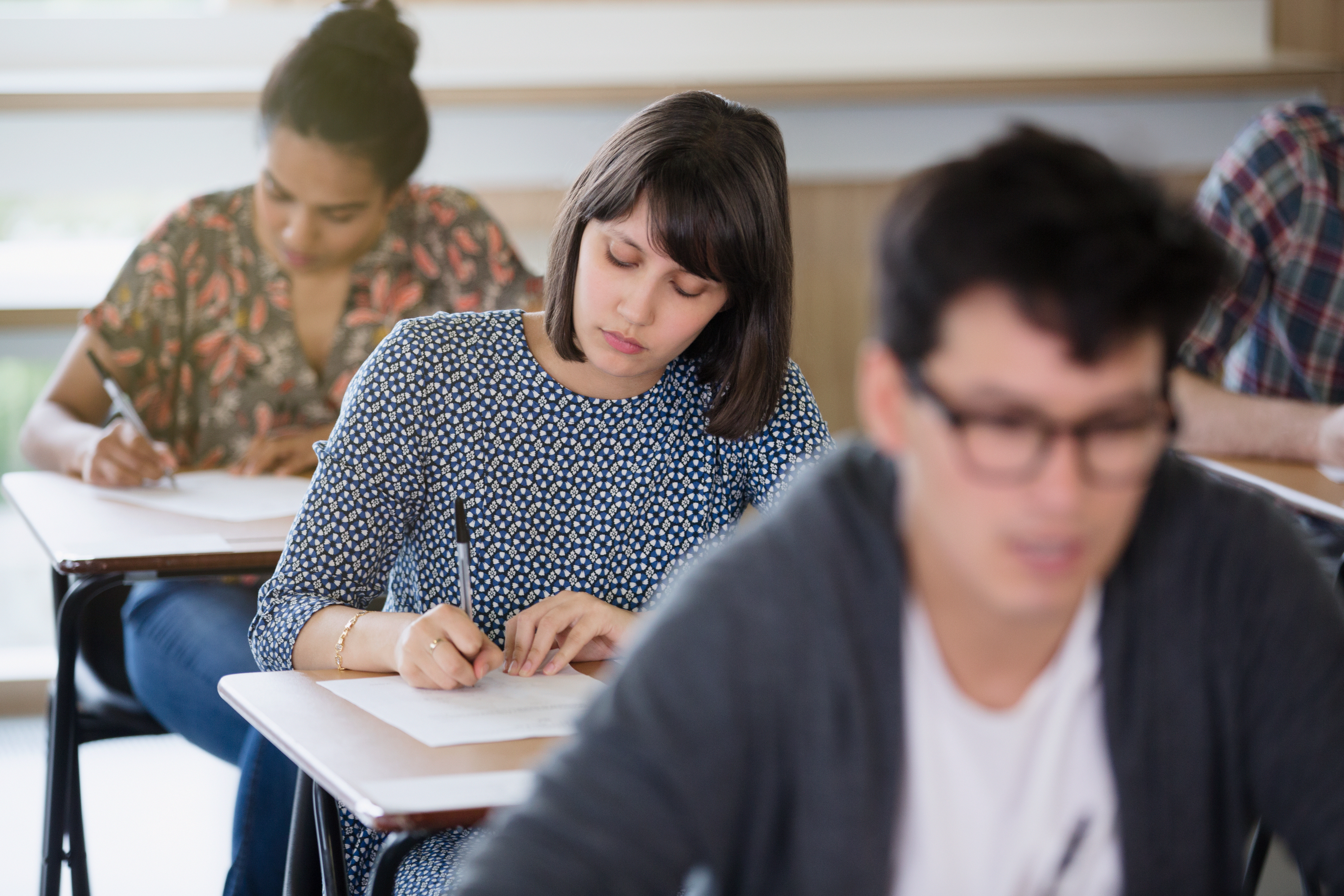 Female college student taking test at desk in classroom