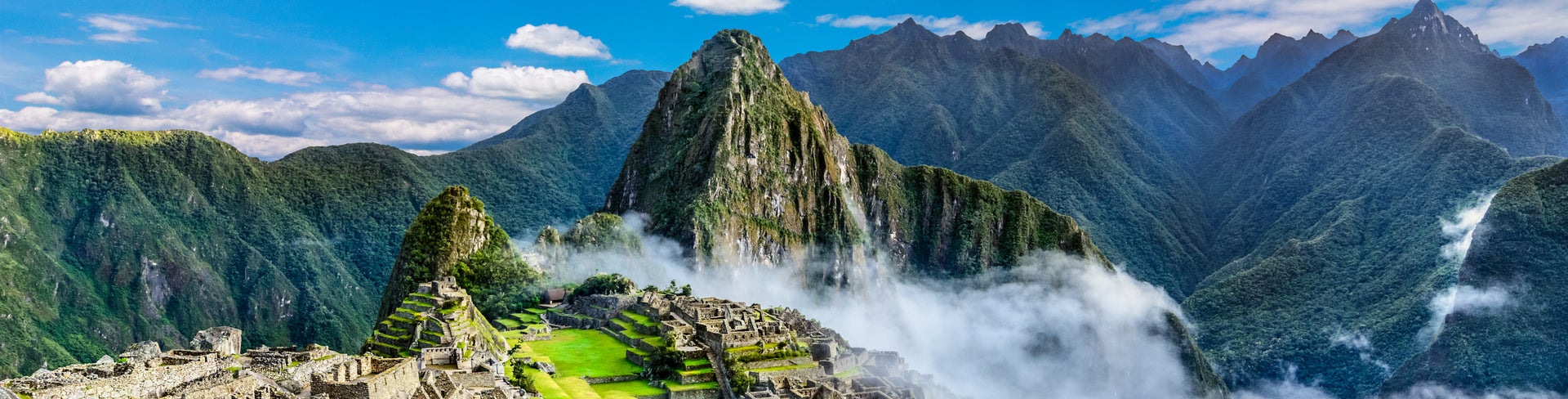 Panoramic view of Machu Picchu ruins in Peru with lush green mountains in the background, UNESCO World Heritage site