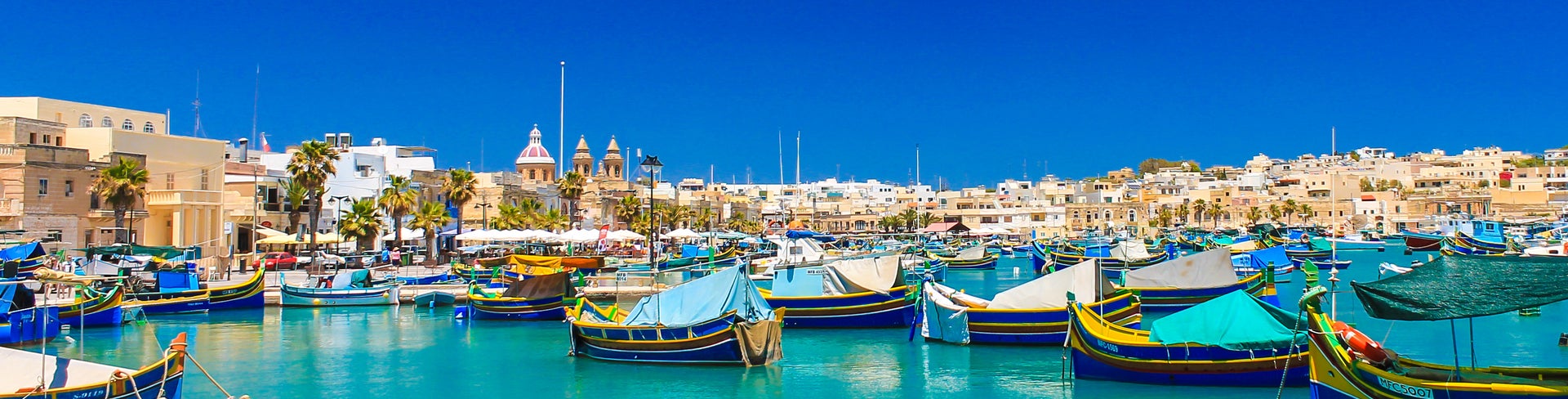 Boats in Malta harbor with historic city center in the background