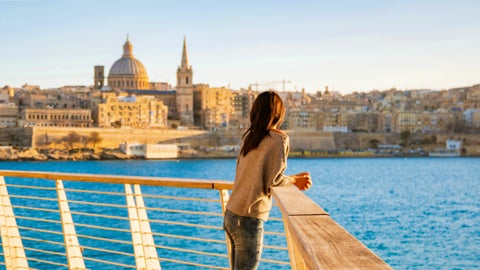 Tourist overlooking Valletta, Malta across the sea, with historic buildings in view