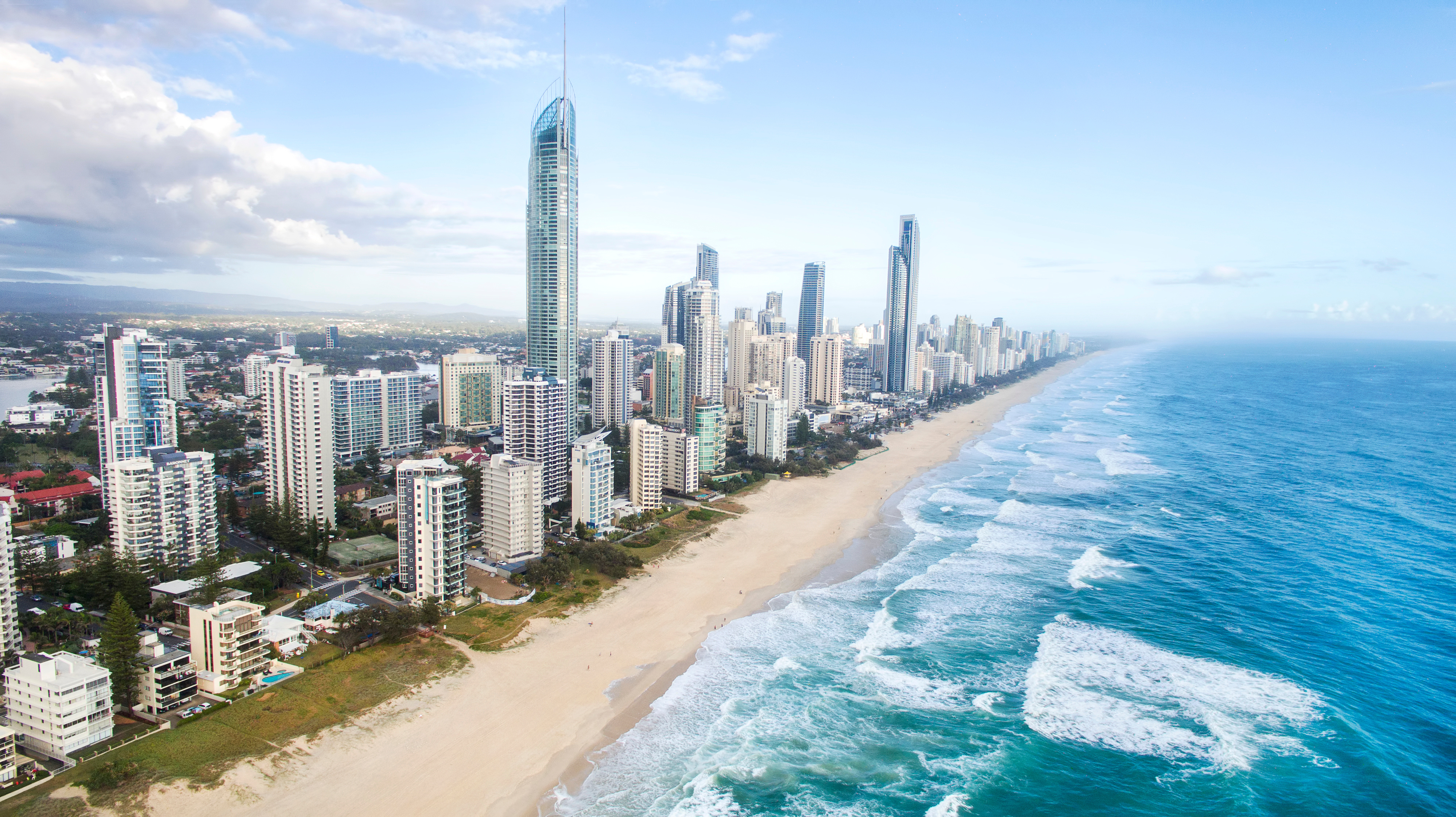 Aerial view of Gold Coast, Australia featuring white-sand beach with blue ocean and modern skyscrapers