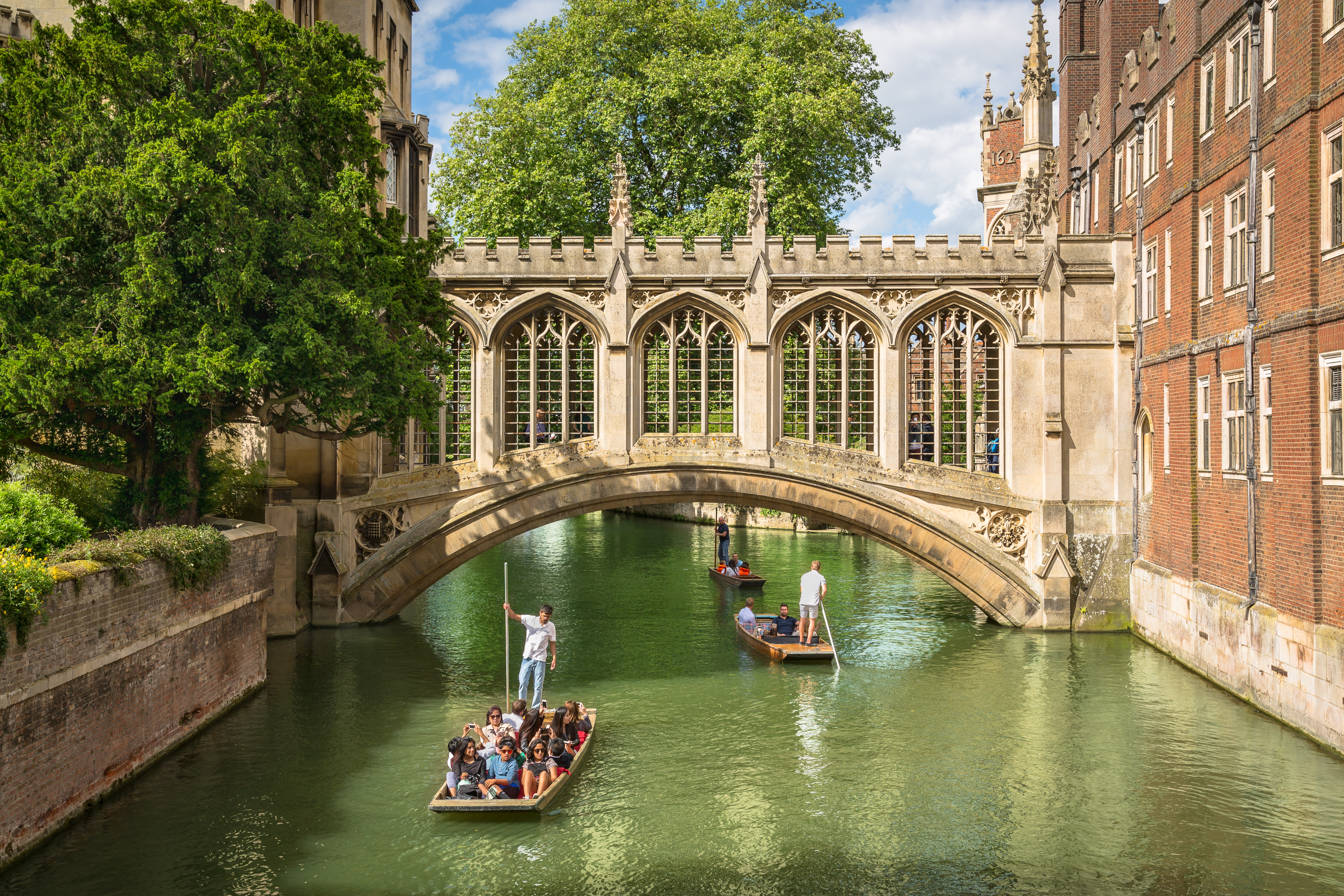 Tourists on small punts boating on the River Cam in Cambridge, passing beneath the historic Bridge of Sighs at St John's College