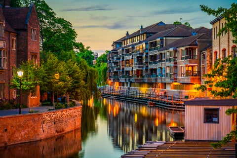 Cambridge waterfront canal with historic buildings illuminated at night, United Kingdom