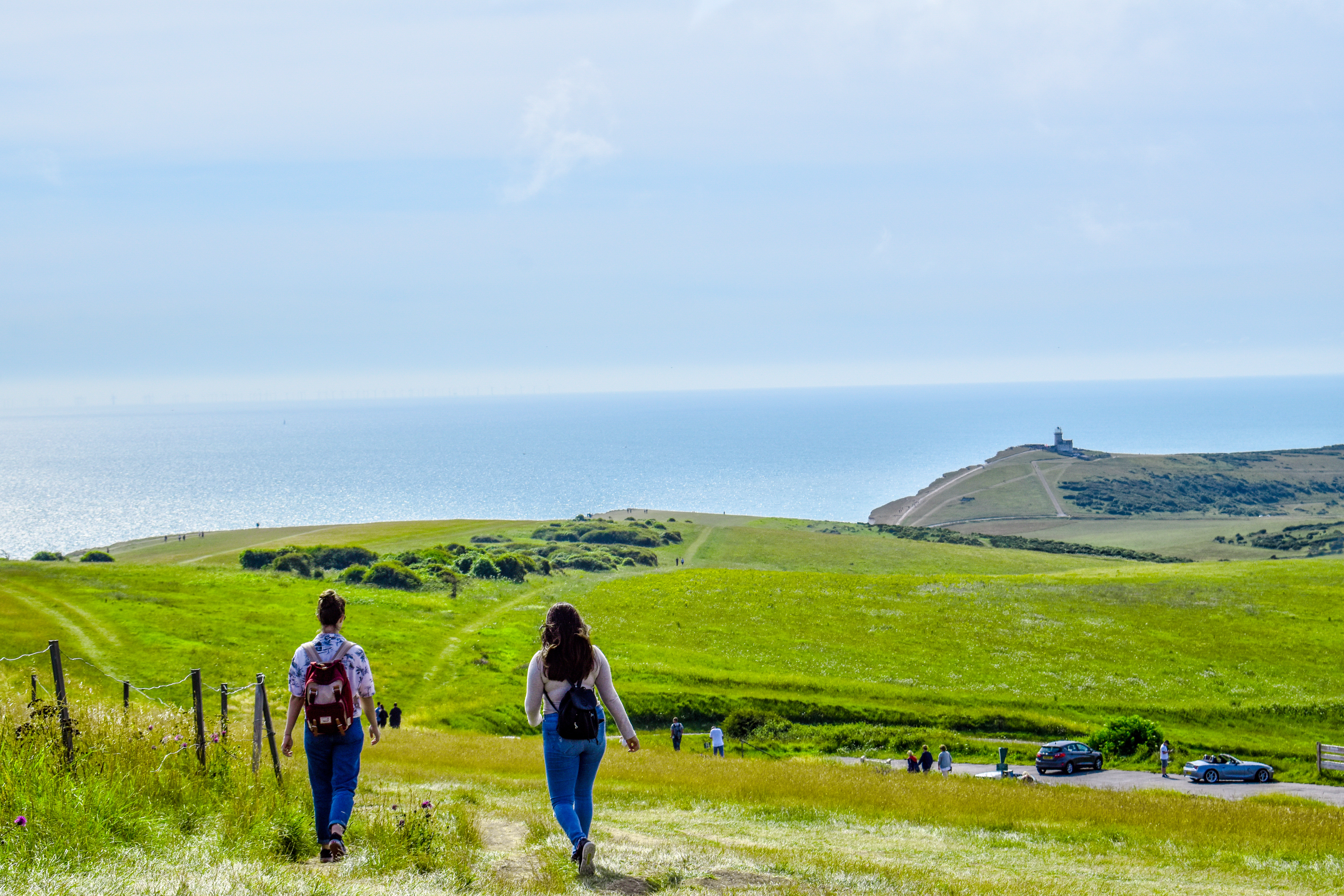 Tourists walking in South Downs National Park with the ocean visible in the background in Wiston, United Kingdom