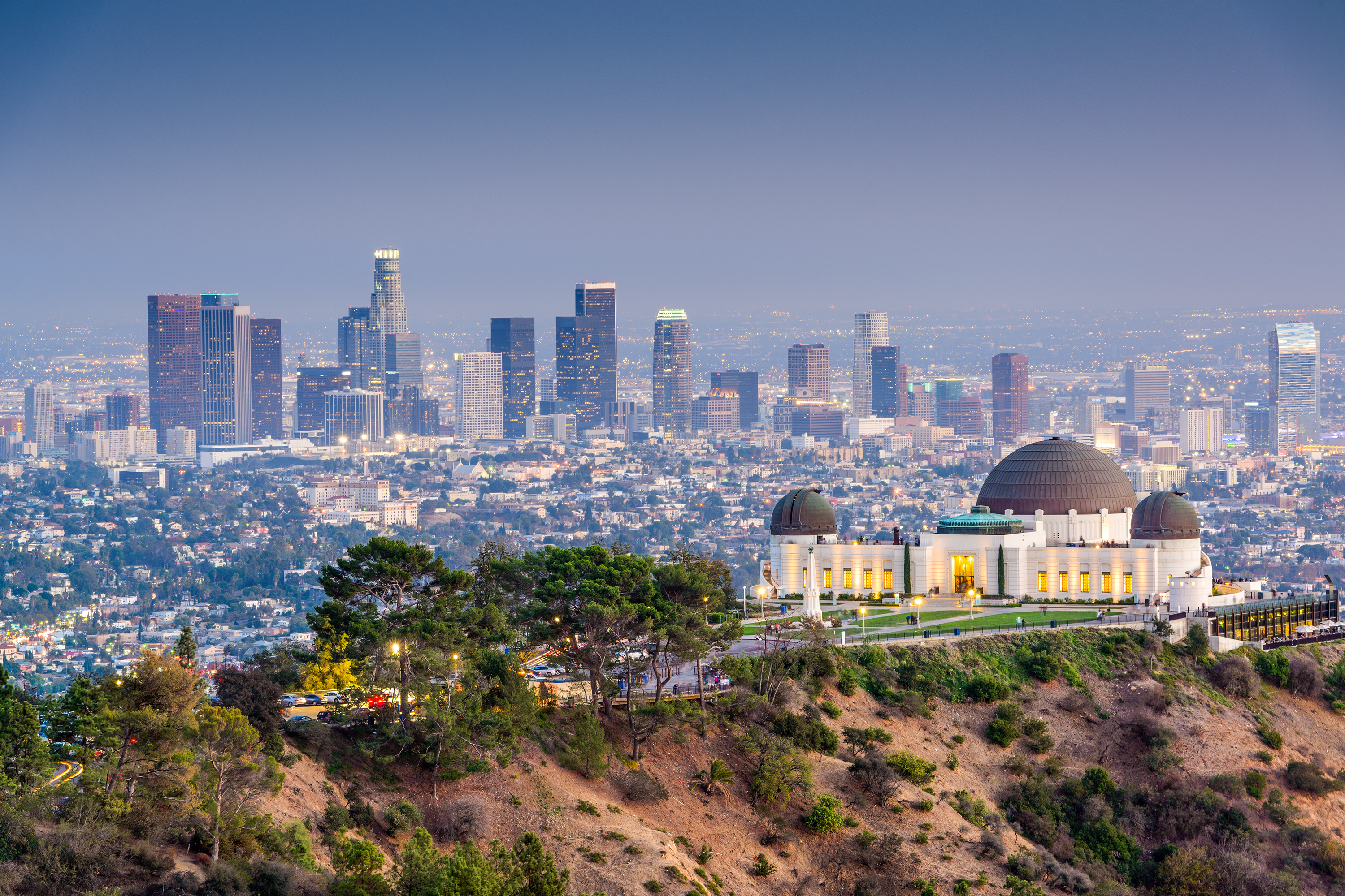 Griffith Observatory at sunset with Los Angeles city skyline in the background showing golden light and scenic urban landscape