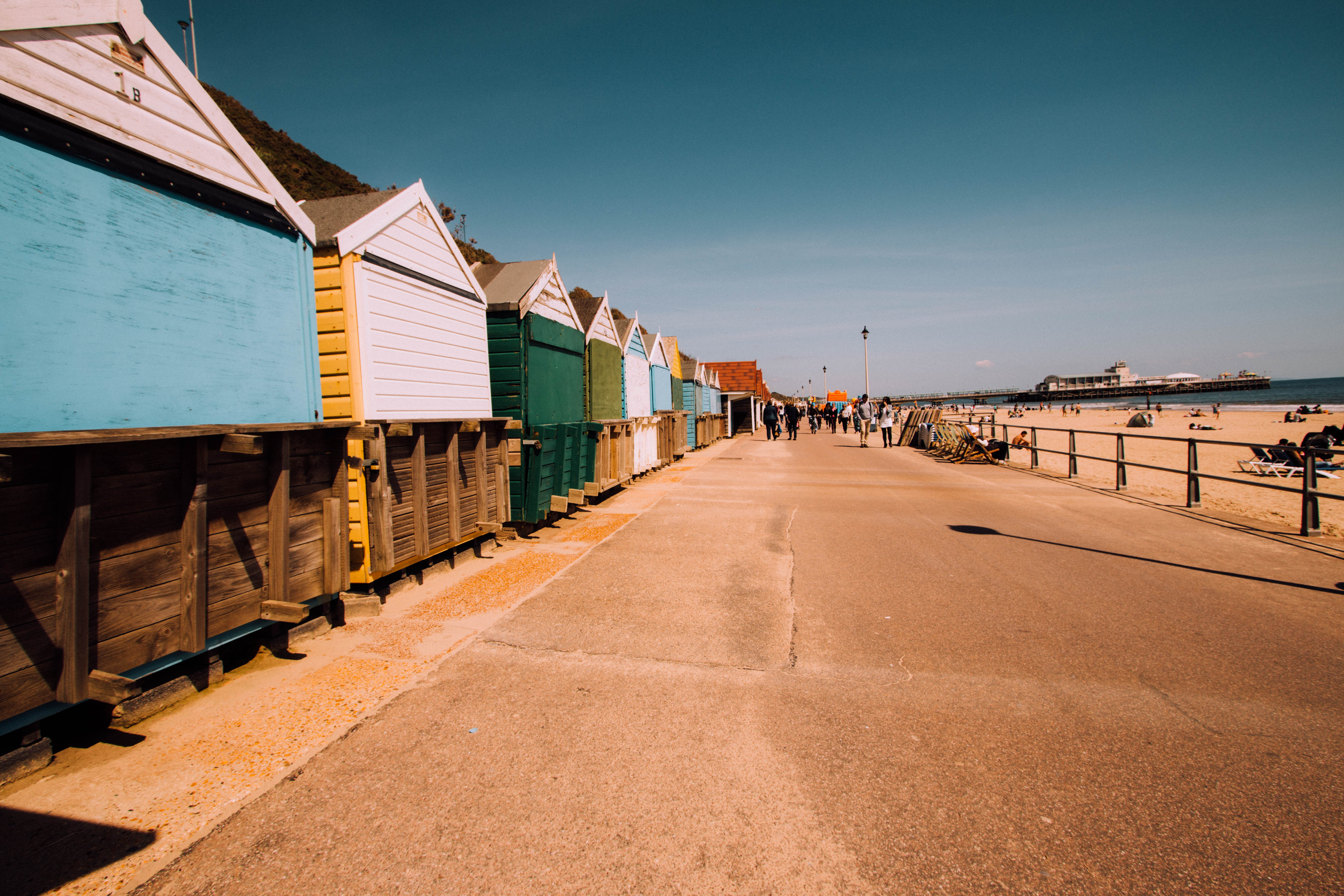 Row of colourful beach huts on a grassy clifftop overlooking the calm sea at Tankerton Beach, Whitstable, Kent, UK, under a clear blue sky