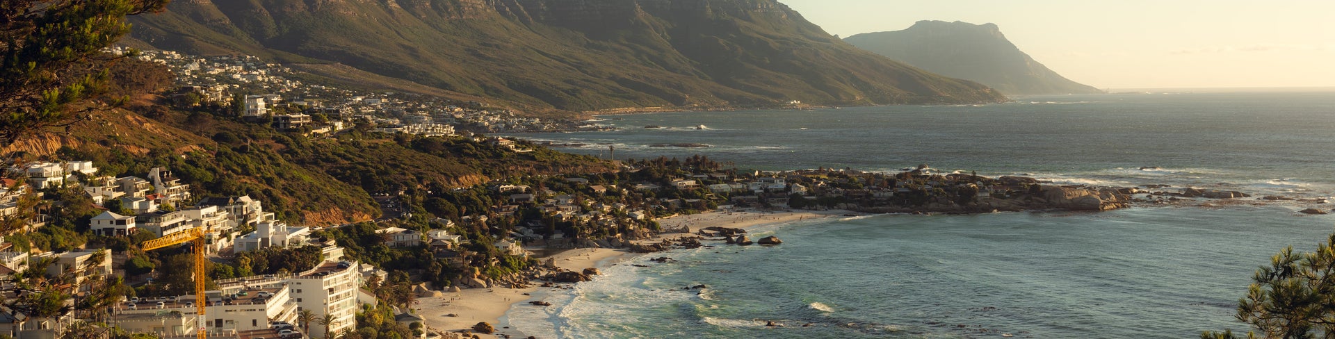 Playa de Camps Bay beach in Cape Town with golden sand, blue waters, and Twelve Apostles mountain range in the background