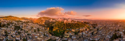 Aerial view of Alhambra fortress in Granada with Sierra Nevada mountains and whitewashed town below