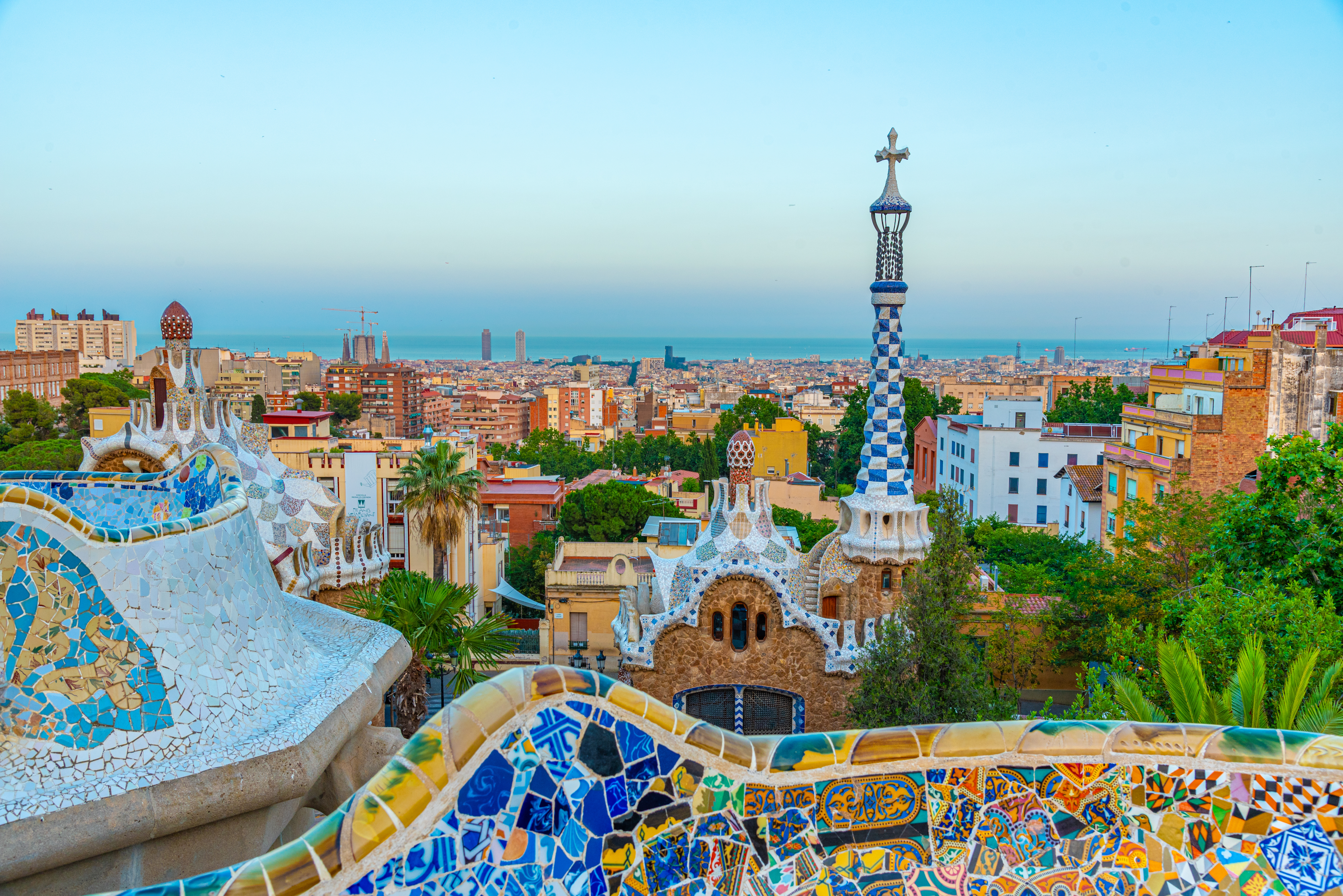 Sunset view of Park Güell in Barcelona, Spain, featuring colorful mosaic architecture and warm light over the city