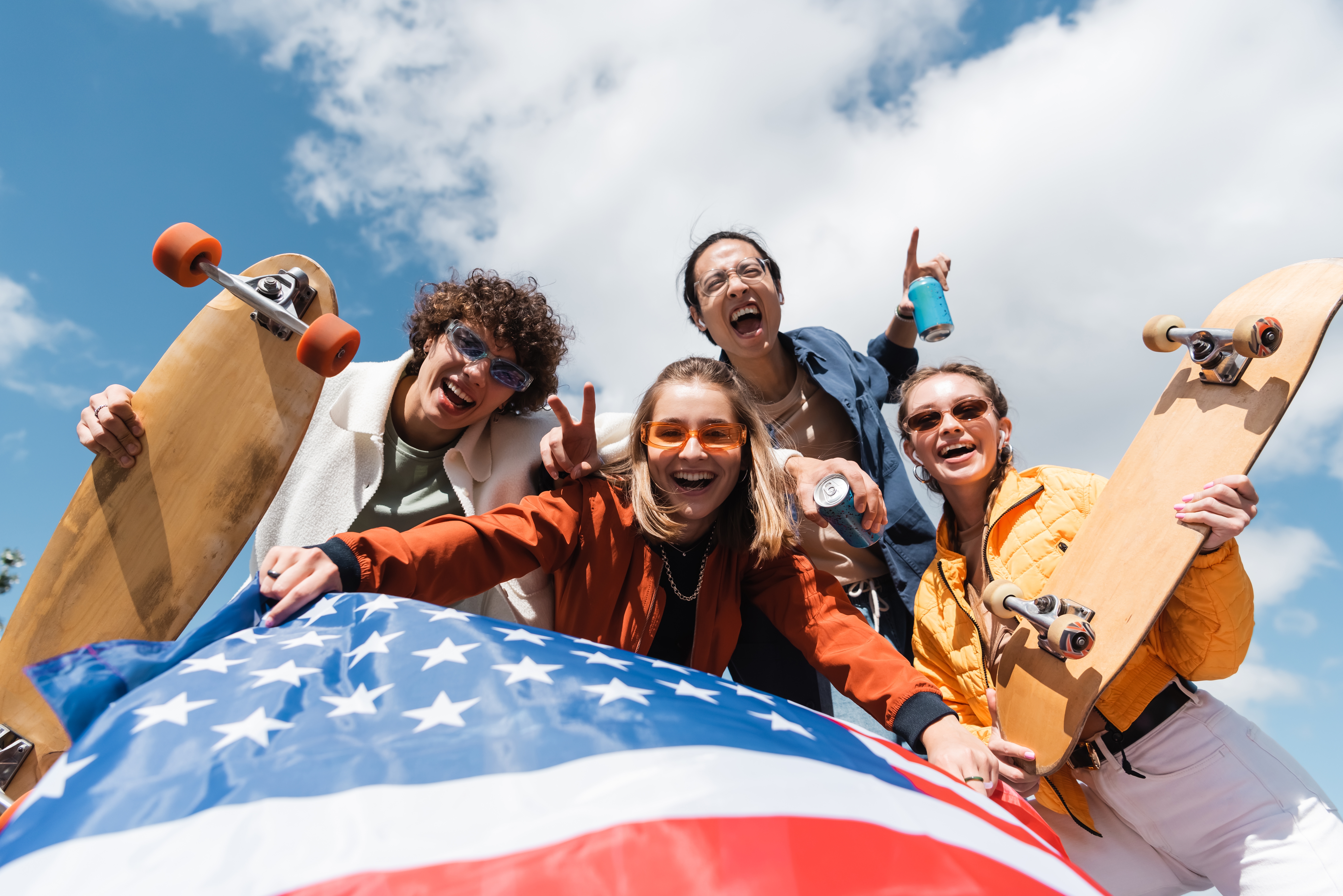 Young people with skateboard and American flag smiling together