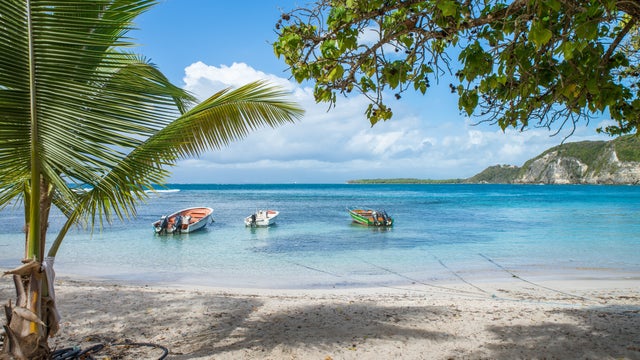 Plage de Petit Havre in Le Gosier, Guadeloupe, features a tranquil beach with soft white sand, turquoise waters, and lush palm trees
