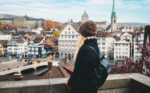 Tourist in Zurich city center, Switzerland, with views of Grossmünster Church, Fraumünster Church, and historic buildings along the Limmat River