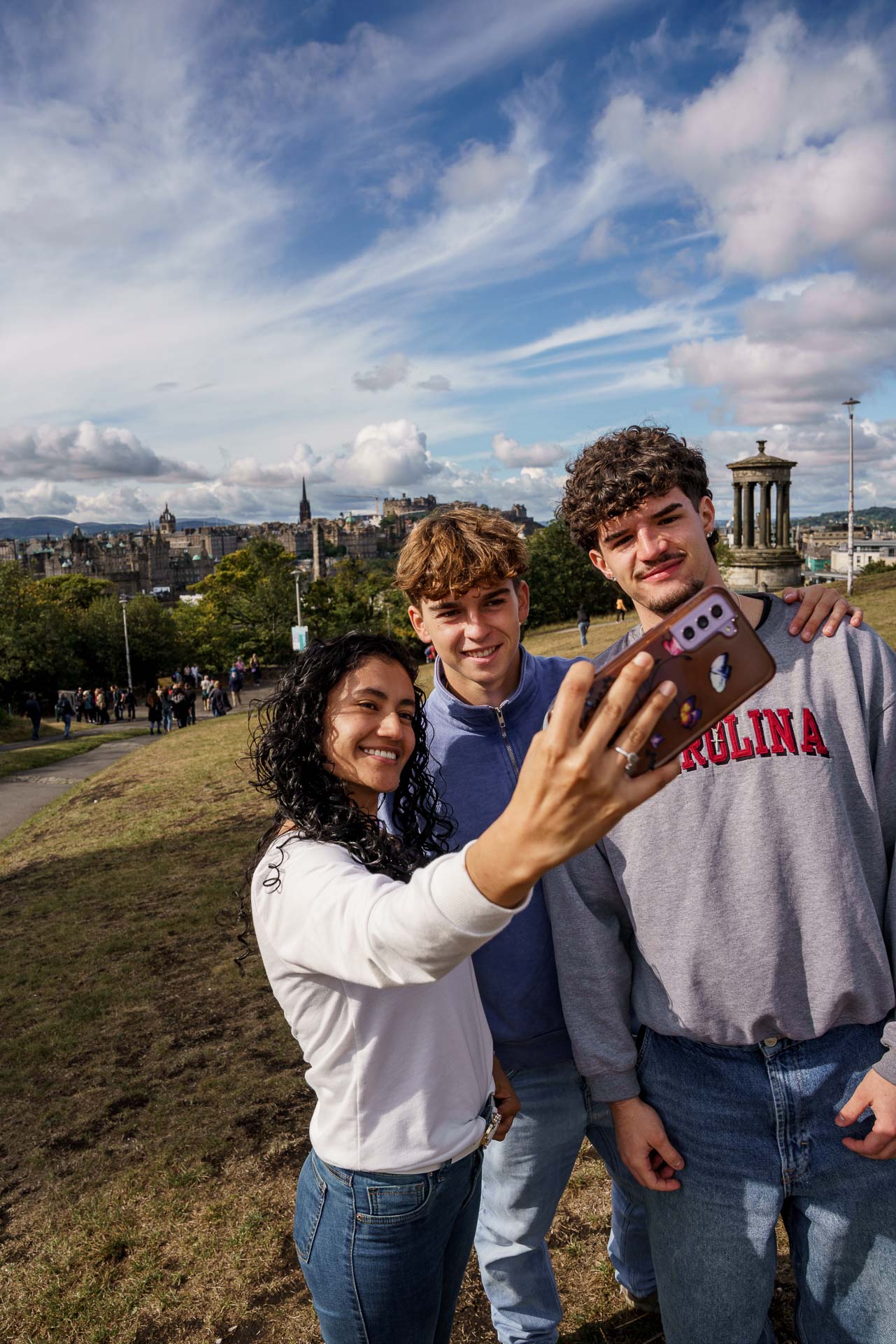 Students taking a selfie on Calton Hill, Edinburgh, with the National Monument and Nelson Monument in the background