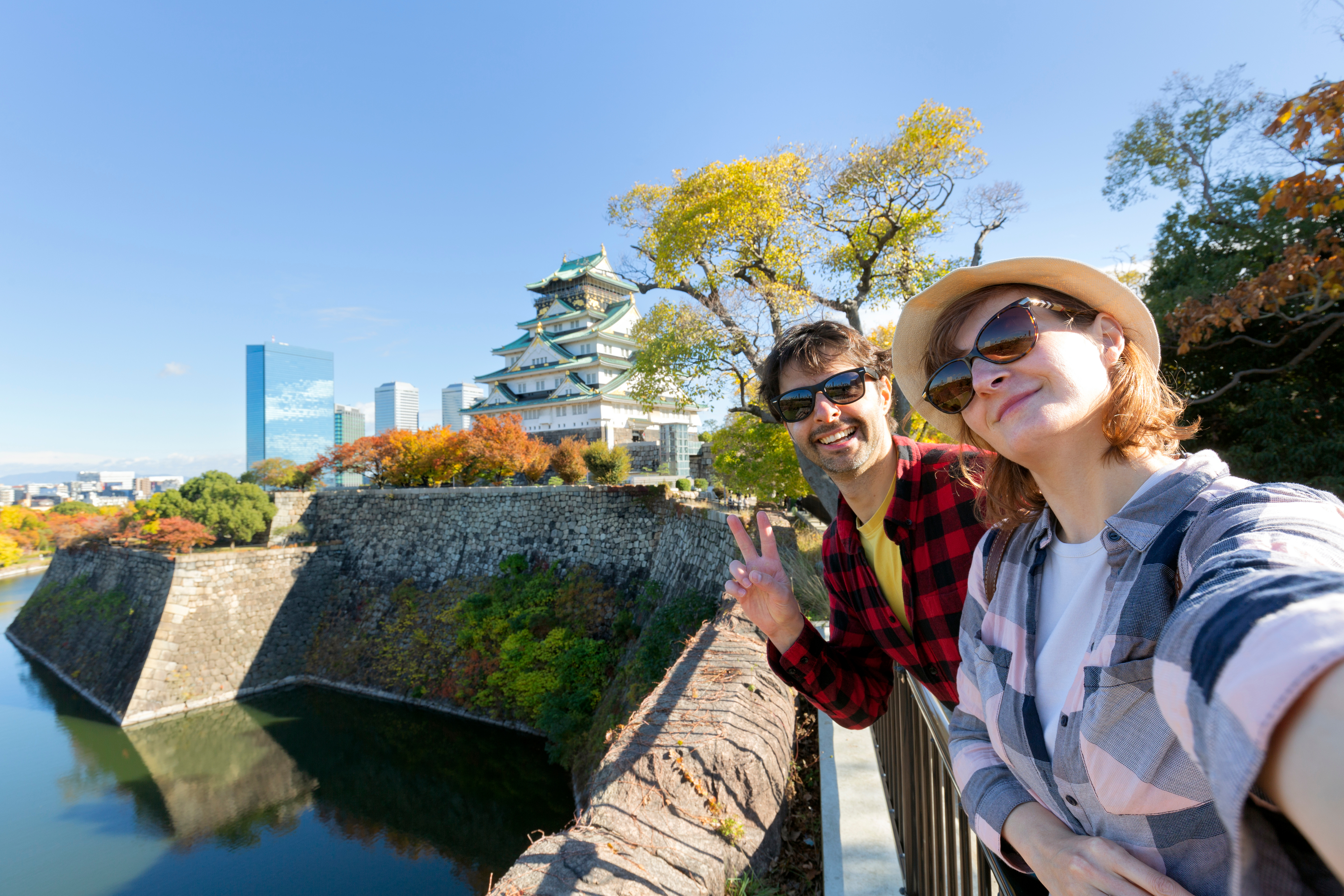 A young travel couple takes a selfie at Osaka Castle