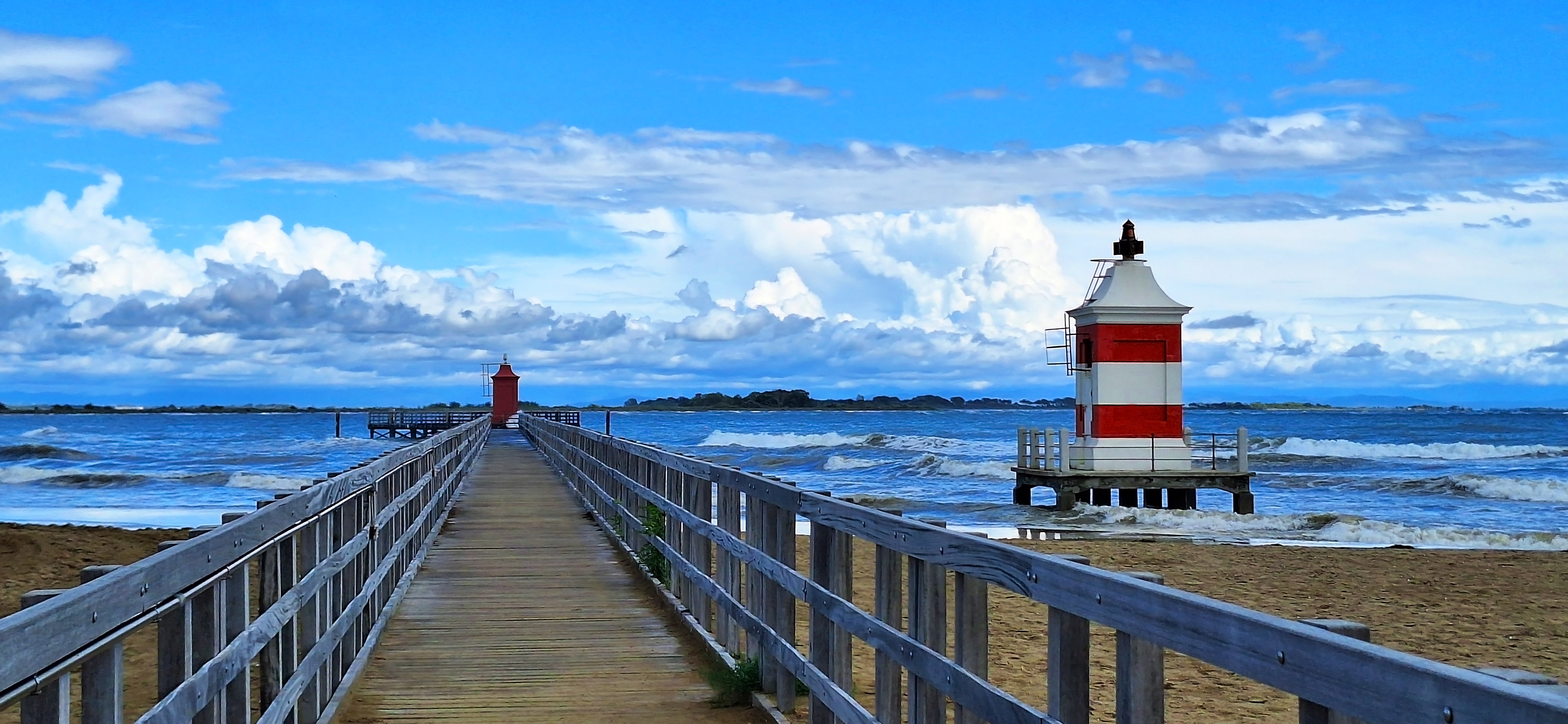 Rustic bridge to the beach alongside a lighthouse in Lignano, Italy