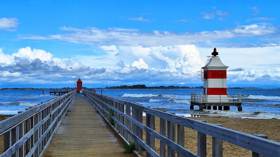 Rustic bridge to the beach alongside a lighthouse in Lignano, Italy