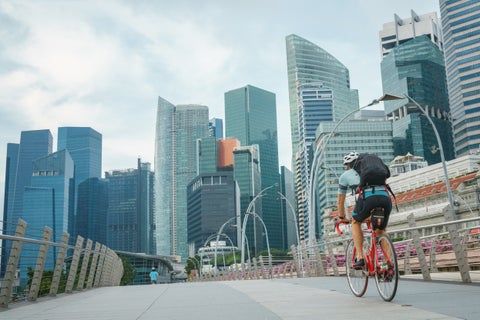 Biker riding in Singapore city with modern skyscrapers towering in the background