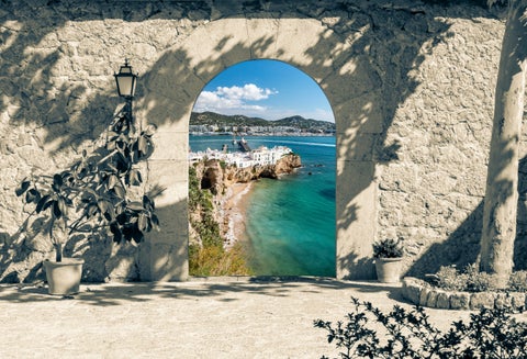 Rustic gate entrance to Cala d’Hort beach in Ibiza, Spain, with white houses and Sa Talaia mountain in the background