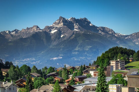 View of Leysin, Switzerland, showing alpine houses nestled among green meadows with mountains in the background
