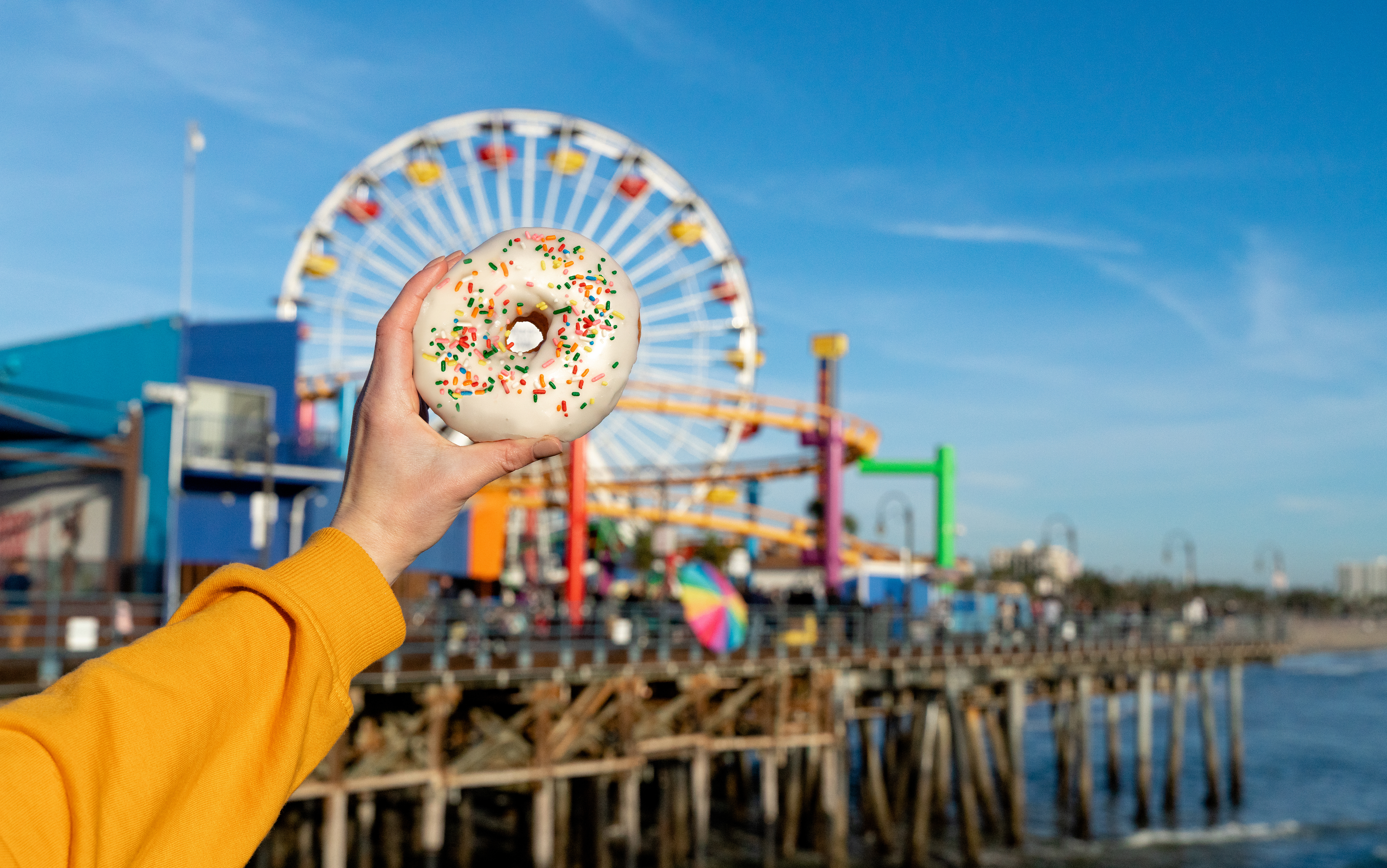 Woman holding donut on Santa Monica beach California with ocean view