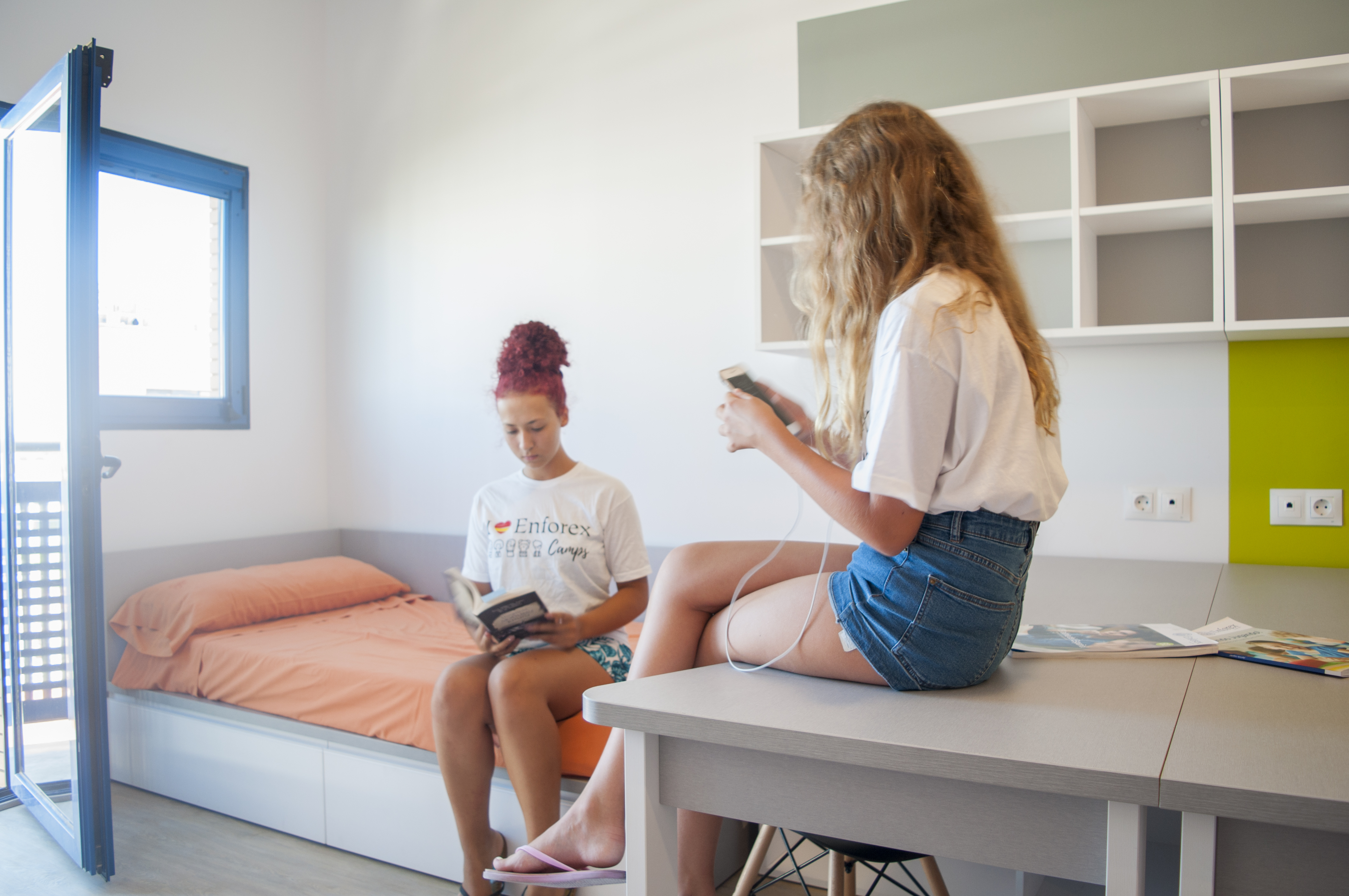 Two girls sitting in their residence bedroom
