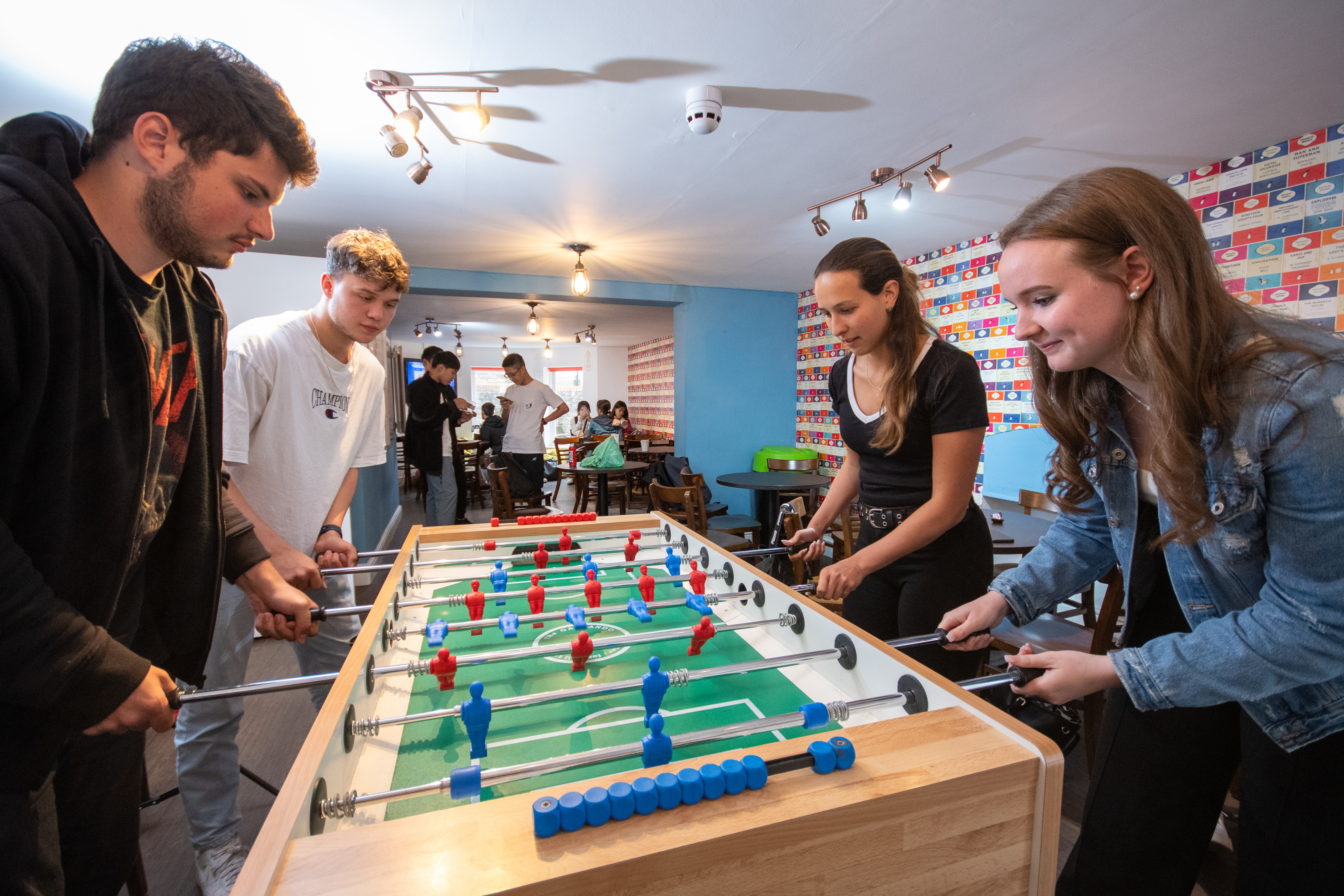 Four students playing foosball at school