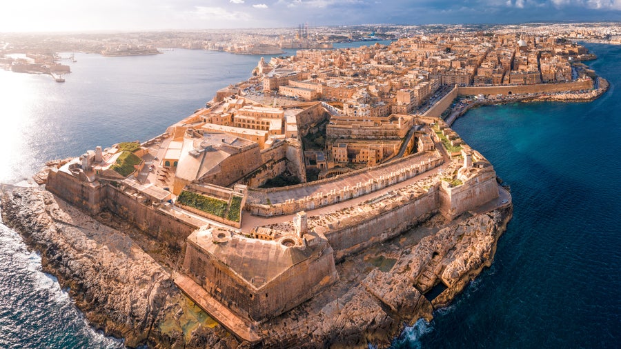 Aerial view of Valletta, Malta surrounded by the Mediterranean Sea, featuring the historic St. John's Co-Cathedral