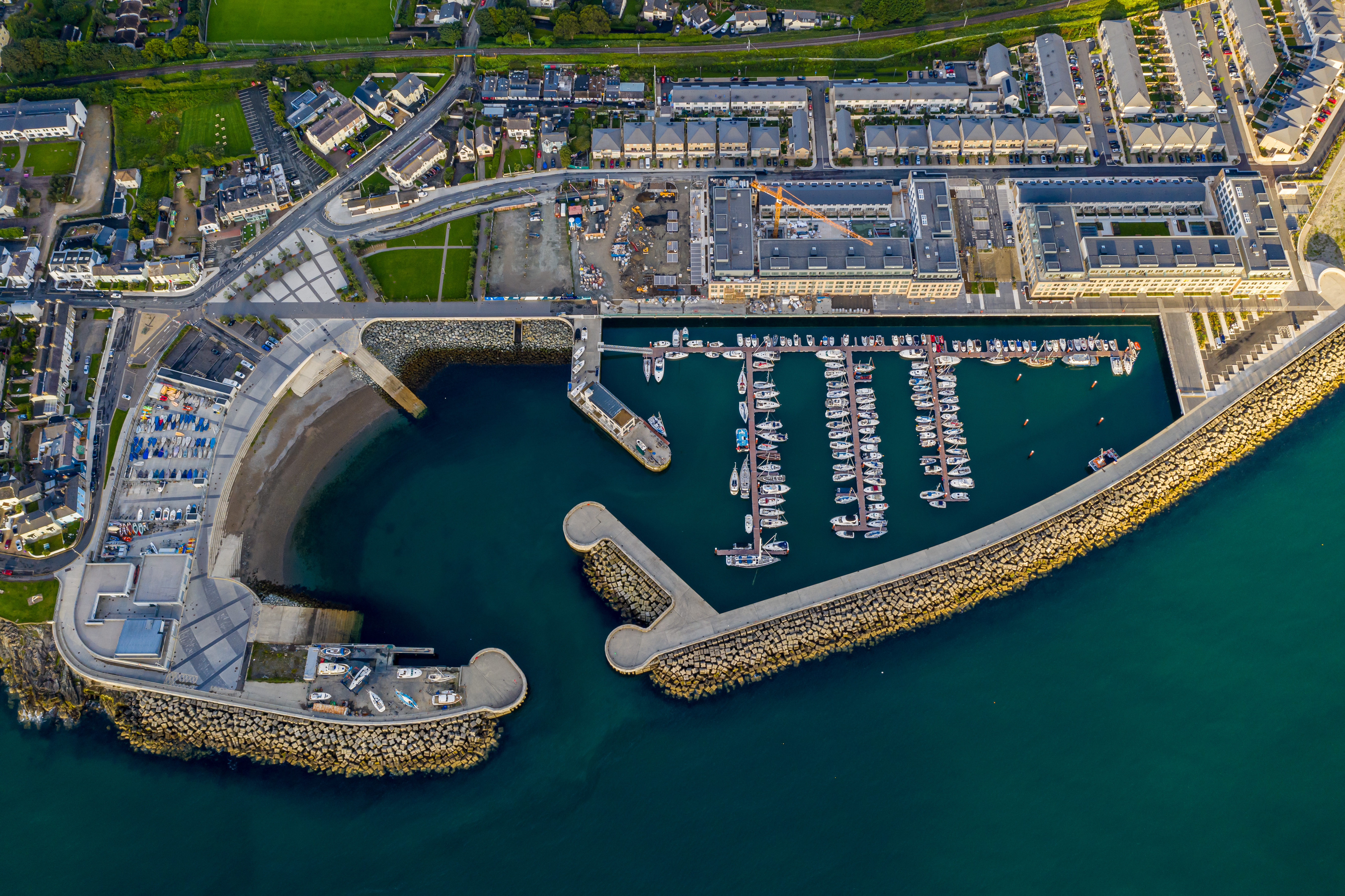 Aerial view of Bray, Ireland, showcasing the harbor with boats, winding roads, residential areas, and surrounding green spaces