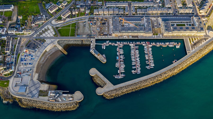 Aerial view of Bray, Ireland, showcasing the harbor with boats, winding roads, residential areas, and surrounding green spaces