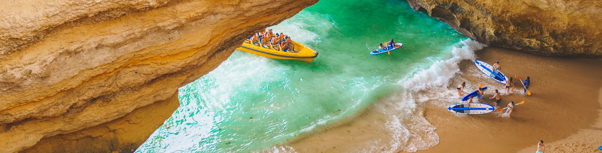 Boat crossing near the limestone rock formations of the Algarve coast at a beach near Faro, Portugal