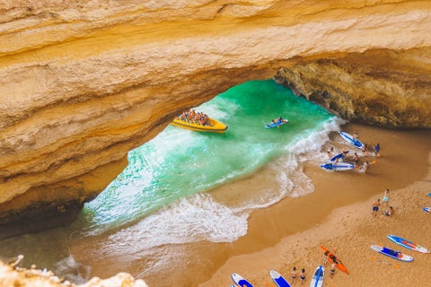 Boat crossing near the limestone rock formations of the Algarve coast at a beach near Faro, Portugal